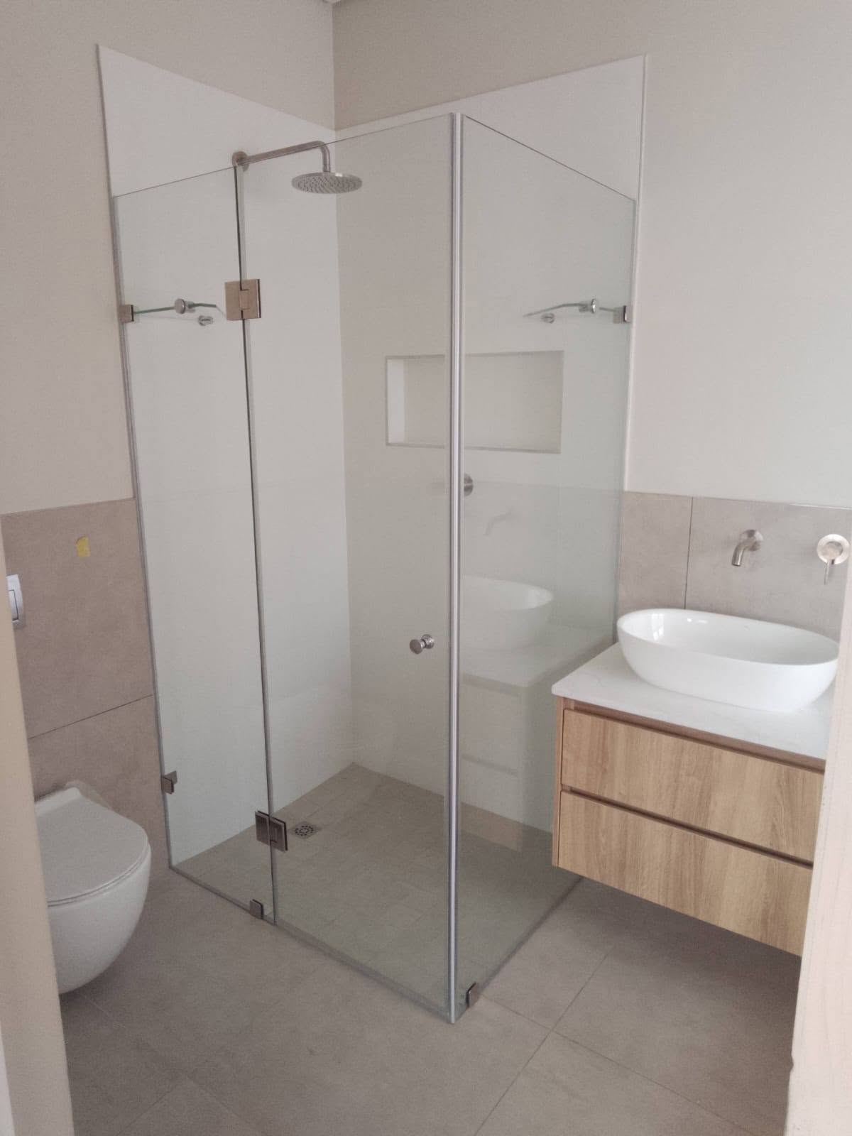 Frameless corner shower beside an oak vanity